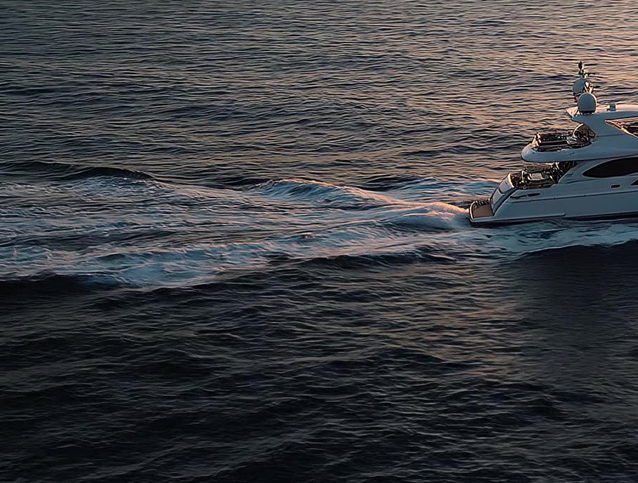 The yacht&rsquo;s white wake trailing across dark blue water